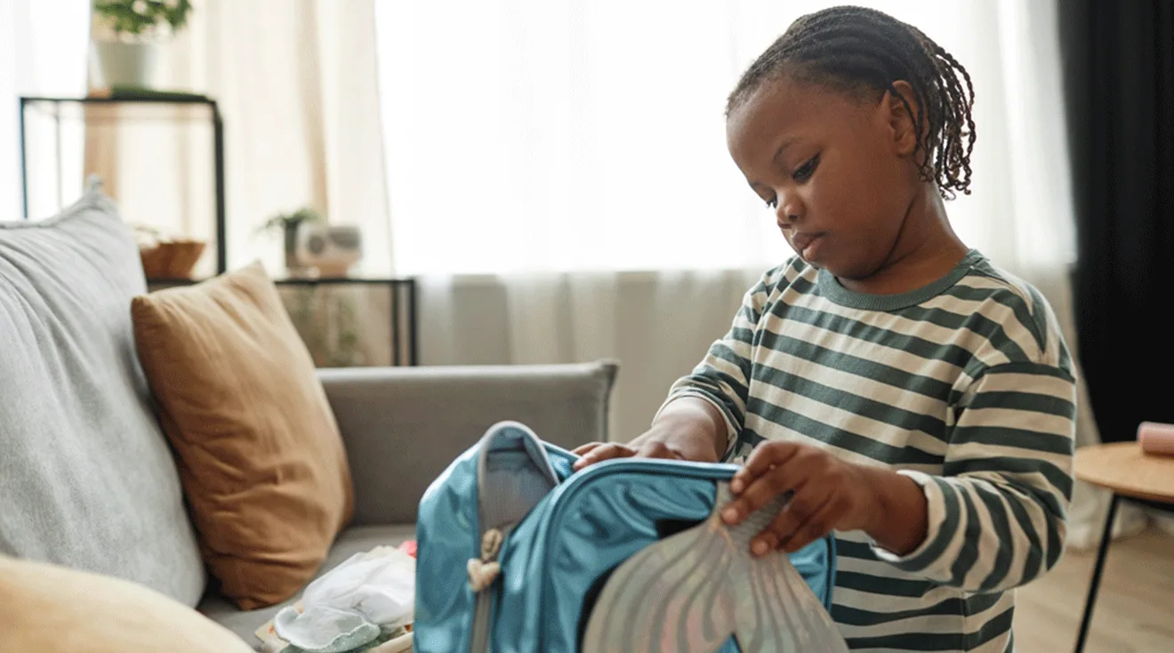 young girl packing backpack at home