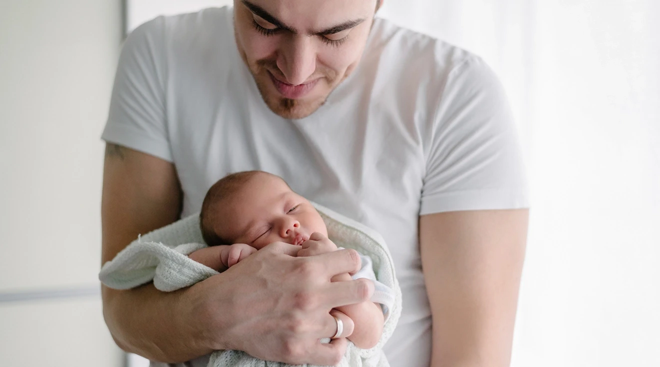 smiling father holding newborn baby