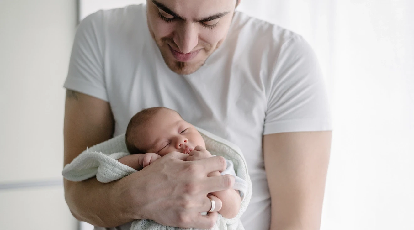 smiling father holding newborn baby