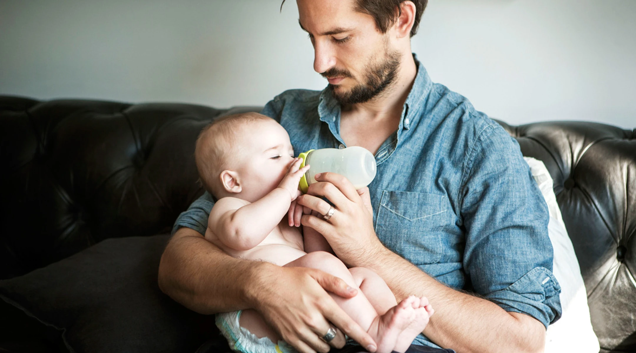 Feeding dad. Мужчина с ребенком на руках. Кормящий папа. Папа кормит младенца. Молодой отец.