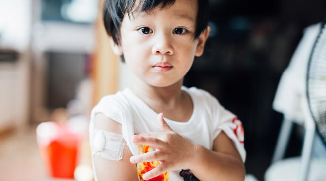 Little boy with bandaid on arm looking at camera 