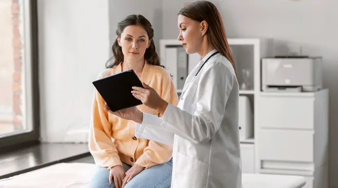 doctor talking to young woman in exam room