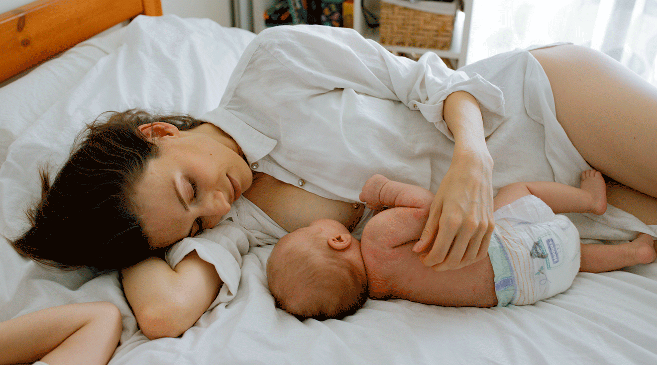 mother breastfeeding while laying in bed on side