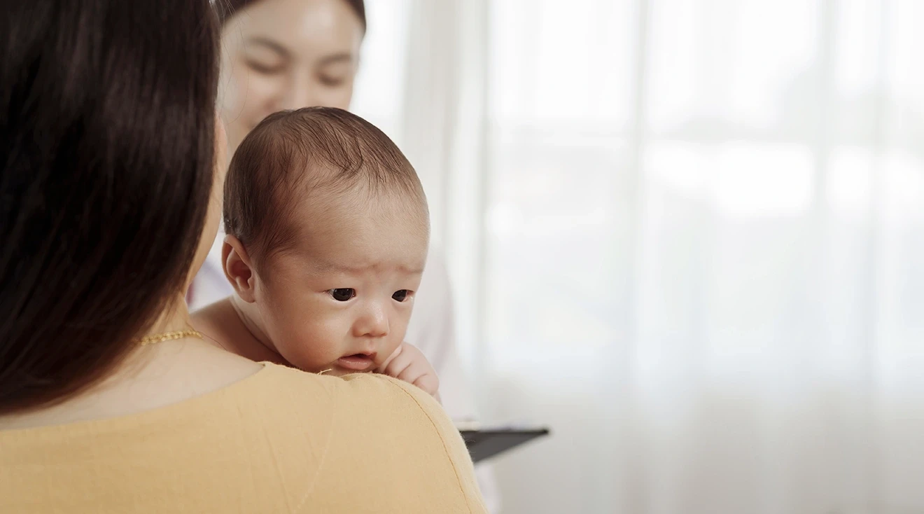 mother holding 2 month old baby at doctor's appointment