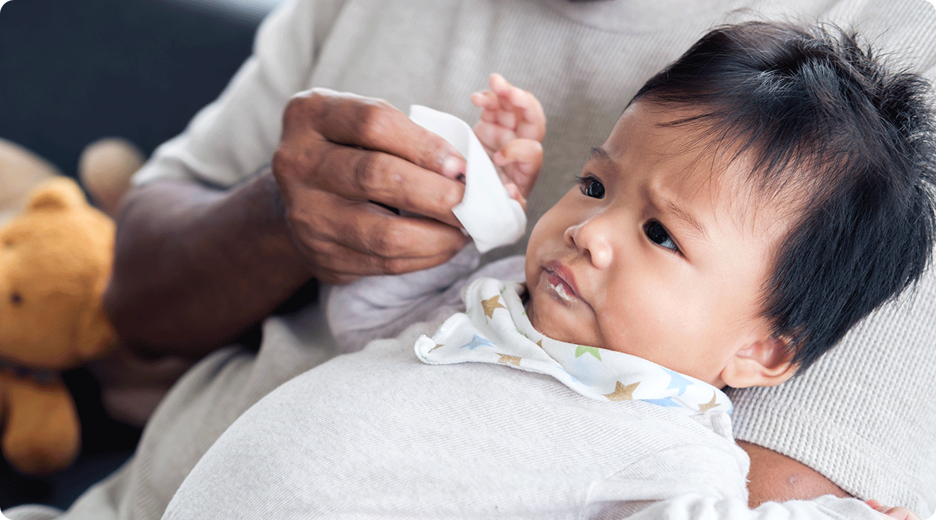 dad wiping baby's mouth after spitting up