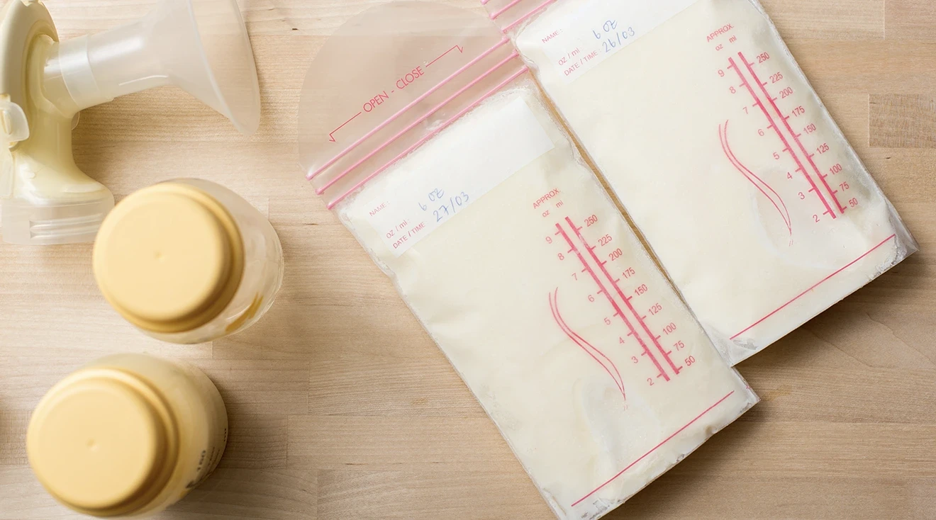 breast milk bags and bottles with breast pump on wooden table