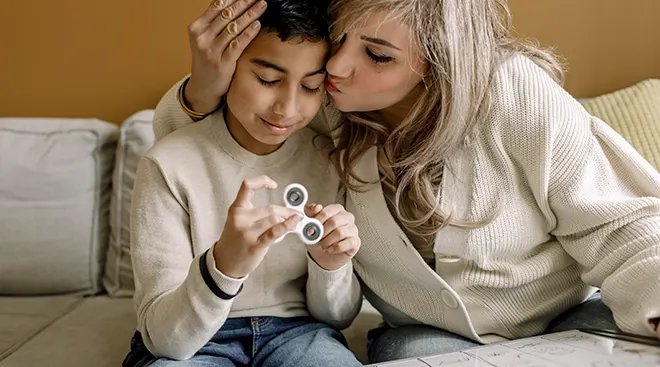 mother kissing autistic son on forehead while teaching school at home