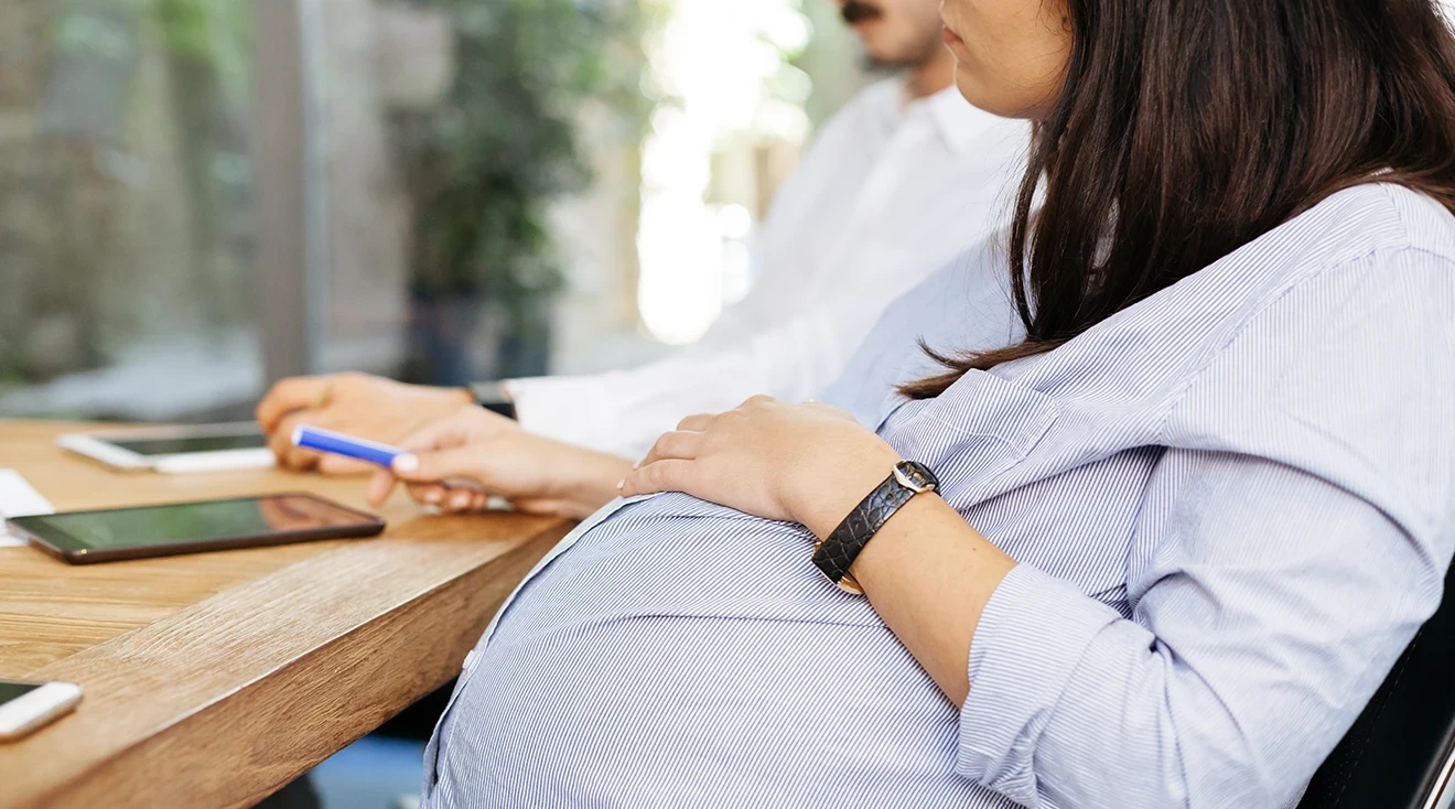 pregnant business woman sitting at a work meeting