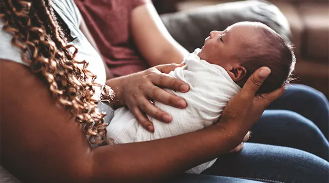 close-up of mom holding her newborn baby with dad in the background