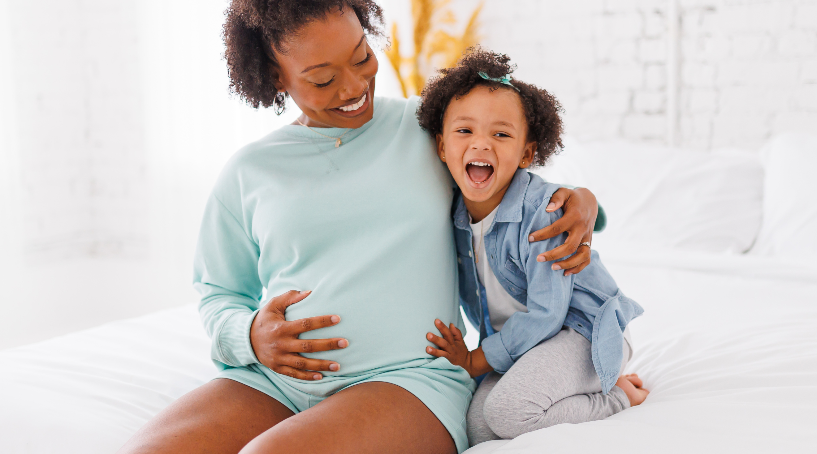 pregnant mom holding belly with toddler next to her