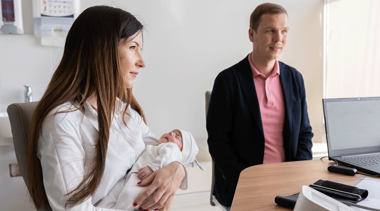 mother and father talking to a pediatrician with newborn baby