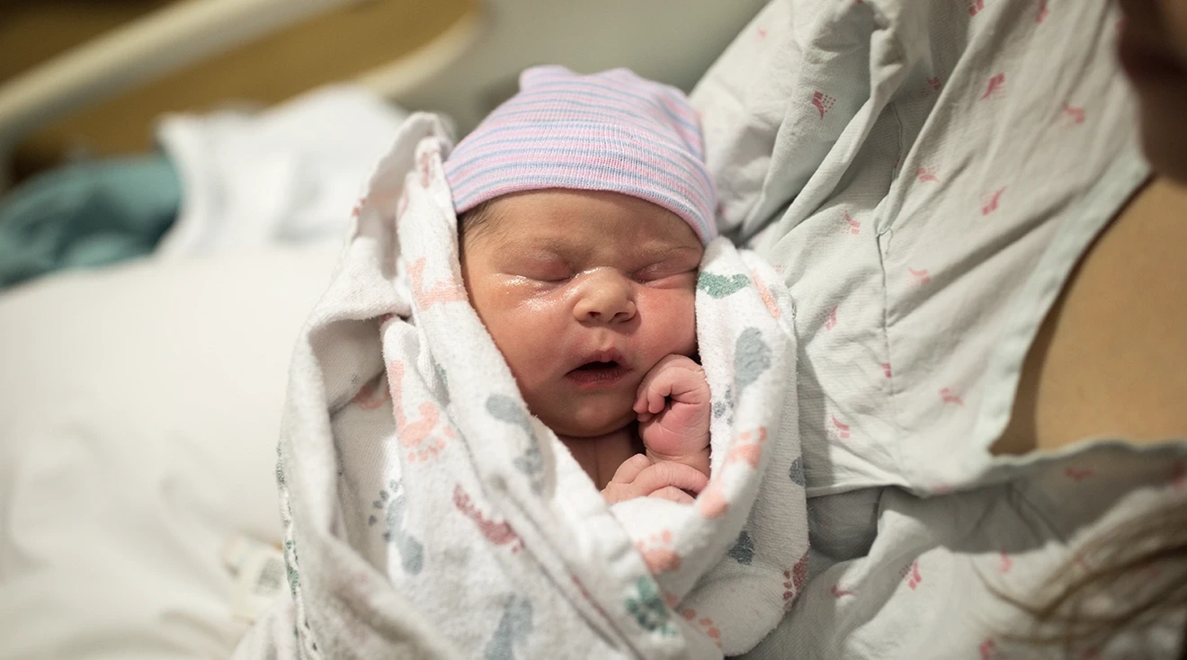 mother holding newborn baby in hospital bed shortly after birth