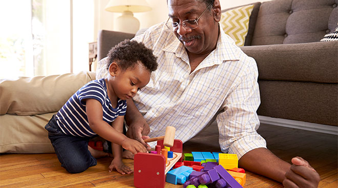 Grandparent playing with peg toy on the floor with baby grandchild.