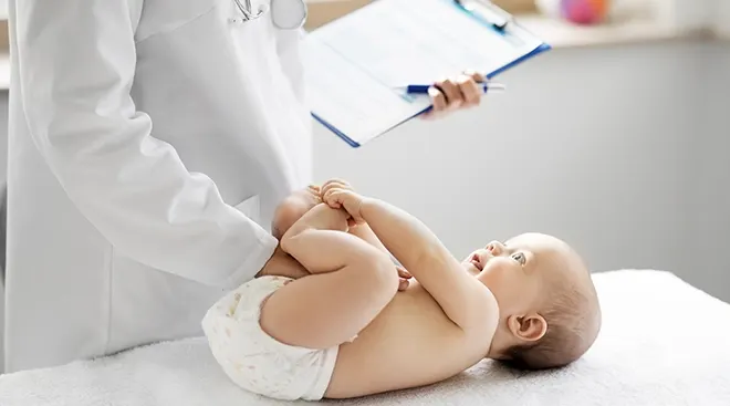 baby lying near doctor with clipboard