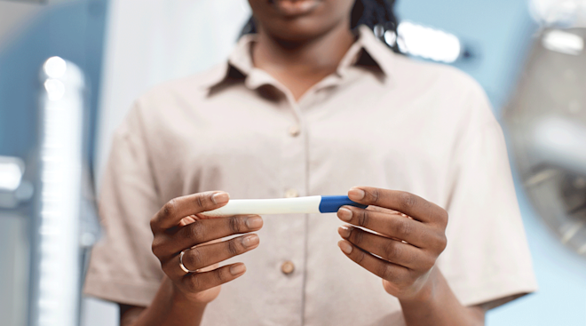 woman holding and looking at a pregnancy test at home