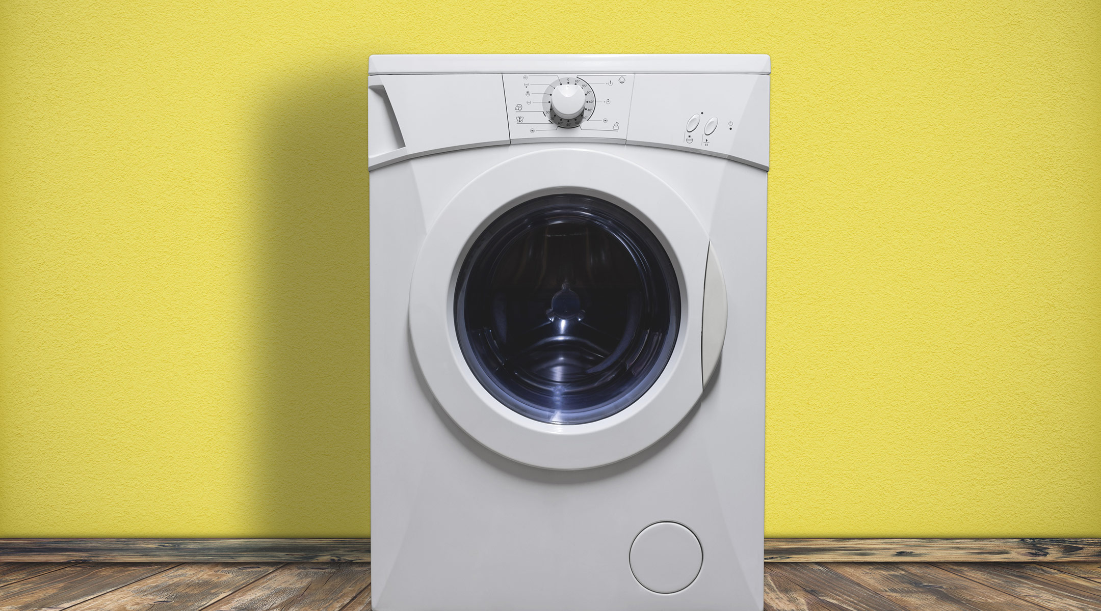 washing machine in front of a yellow wall