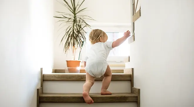 toddler climbing up stairs in home