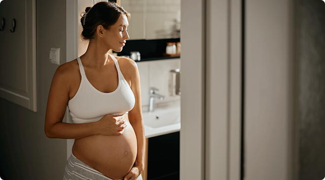 pregnant woman standing in bathroom doorway at home