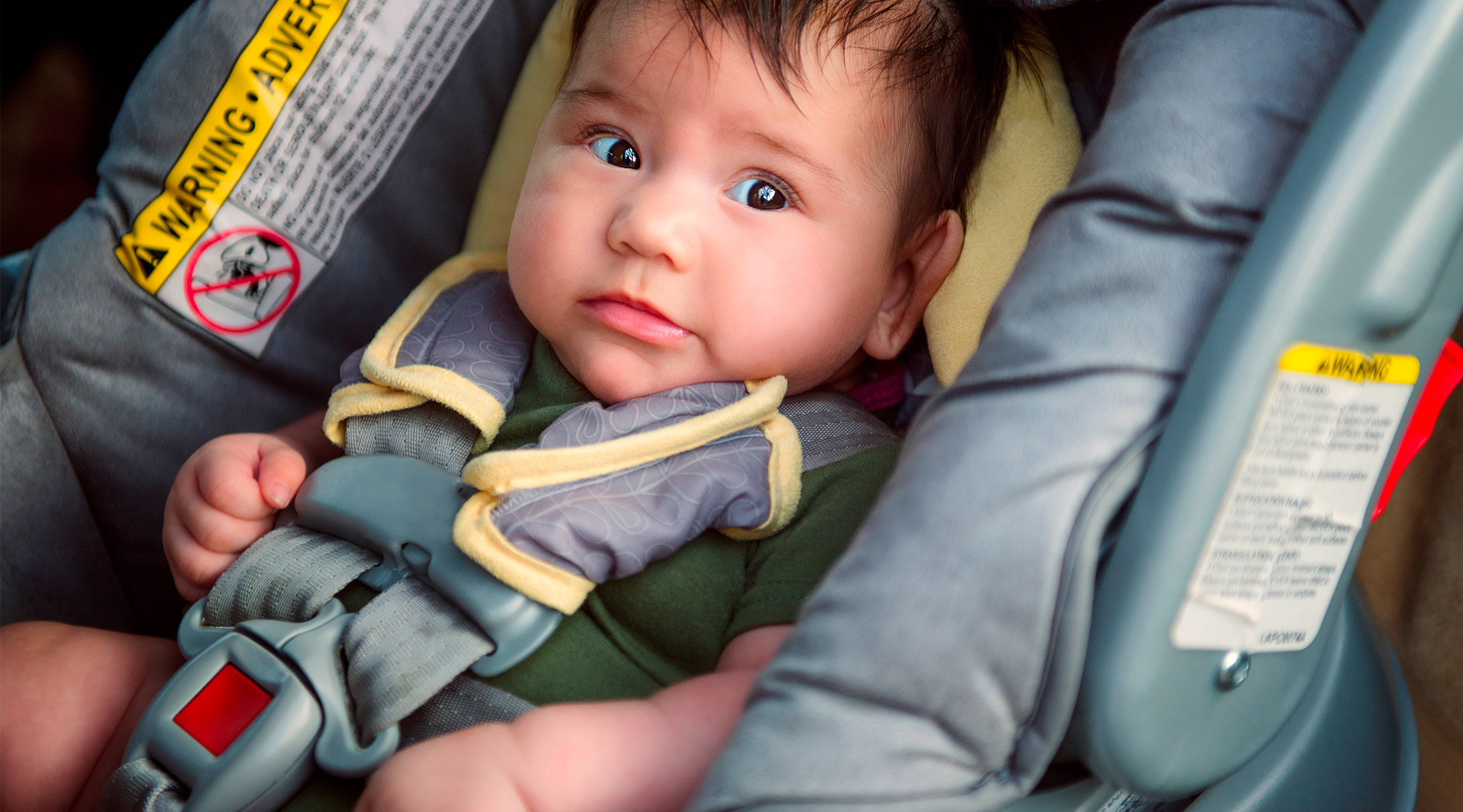 baby sitting in rear facing car seat inside car