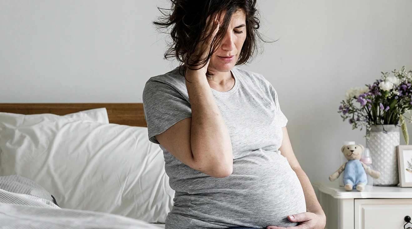 pregnant woman experiencing a migraine at home