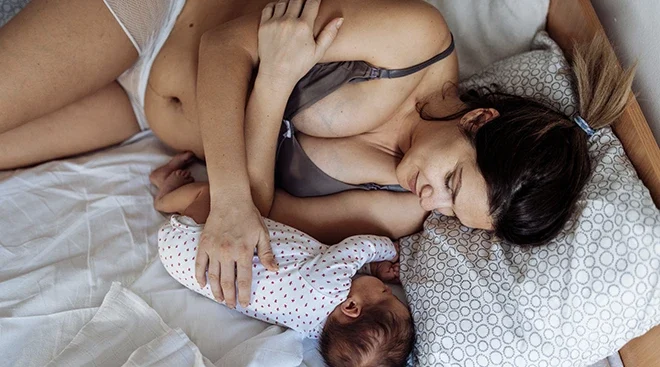 mother lying with newborn baby in bed