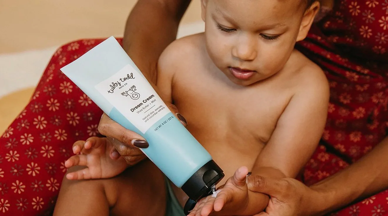 parent putting lotion on baby's hand