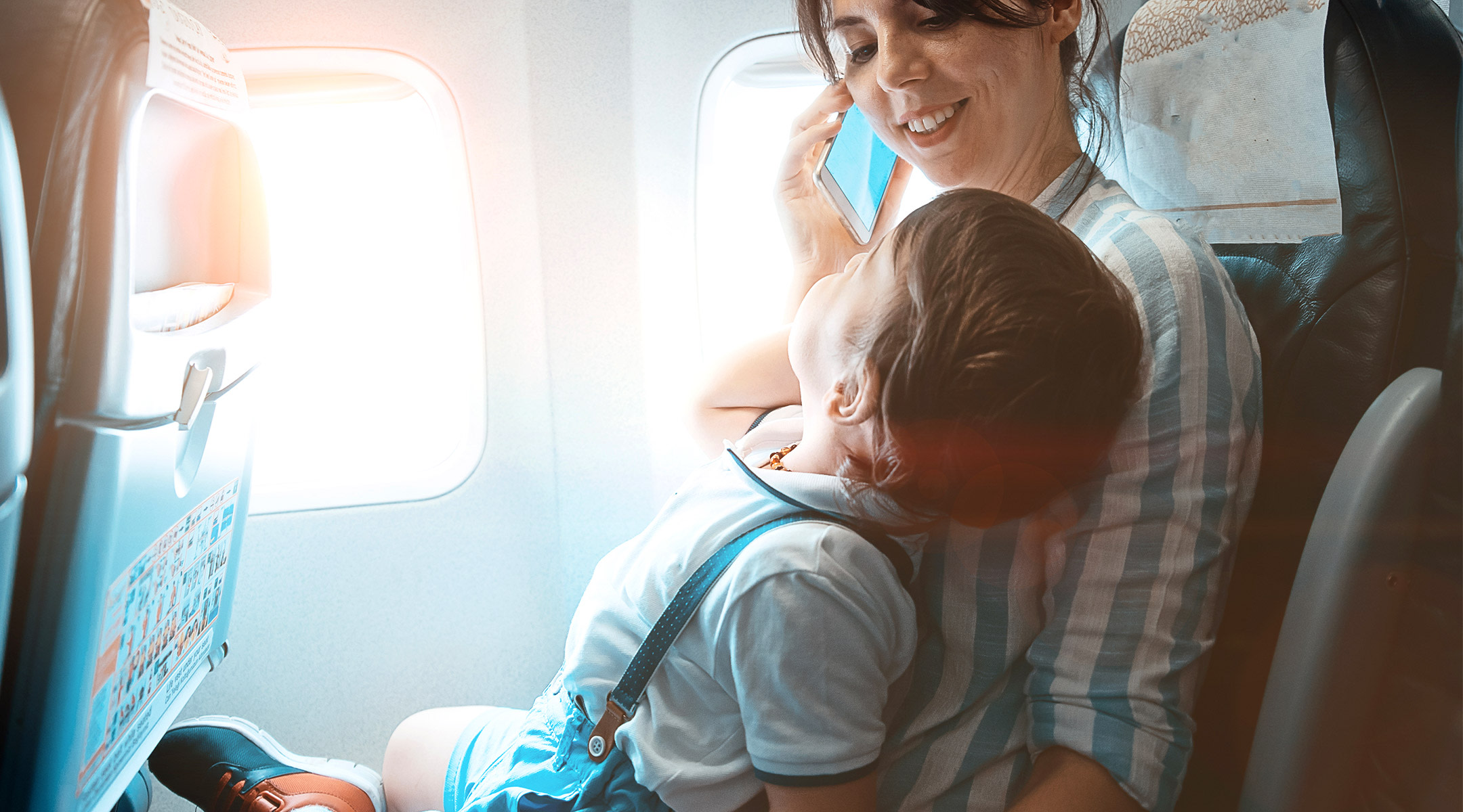 woman flying in airplane with toddler on her lap