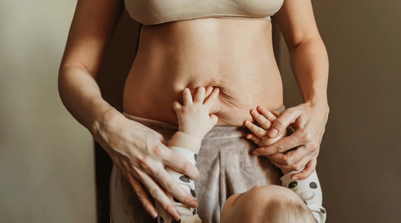 baby touching mom's postpartum belly