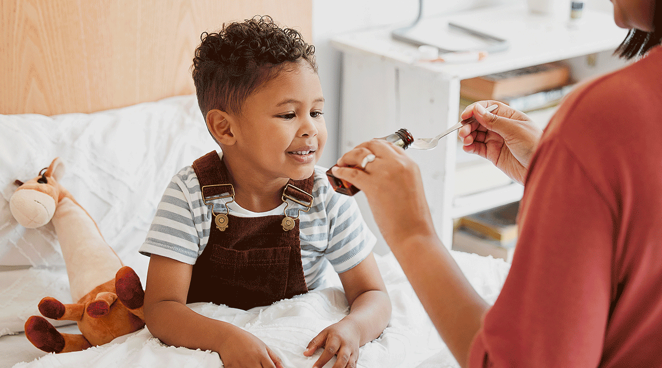 mother giving child medicine in bed