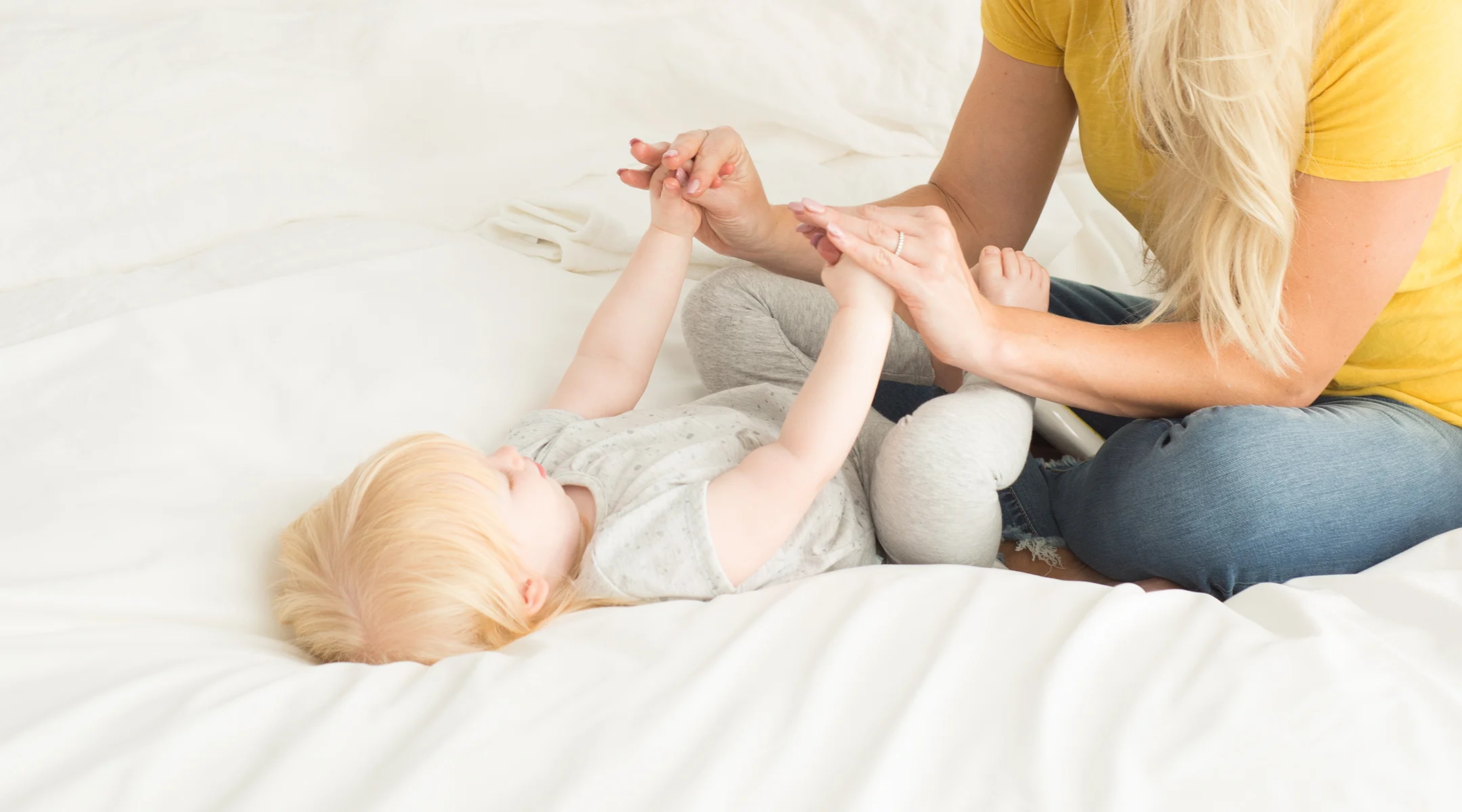 mom playing with baby on bed