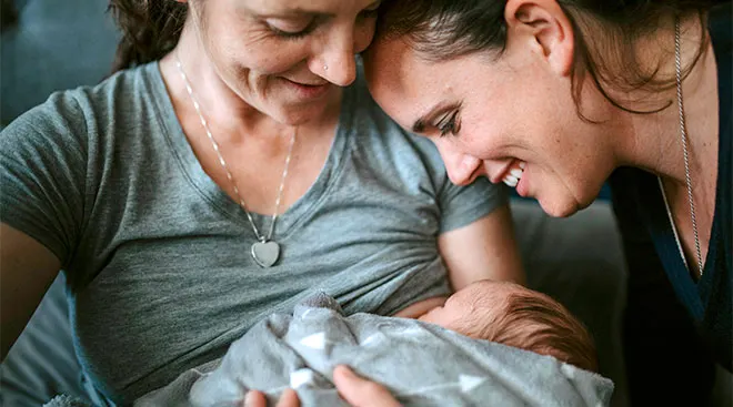 Mom breastfeeds her newborn baby with partner close-by.