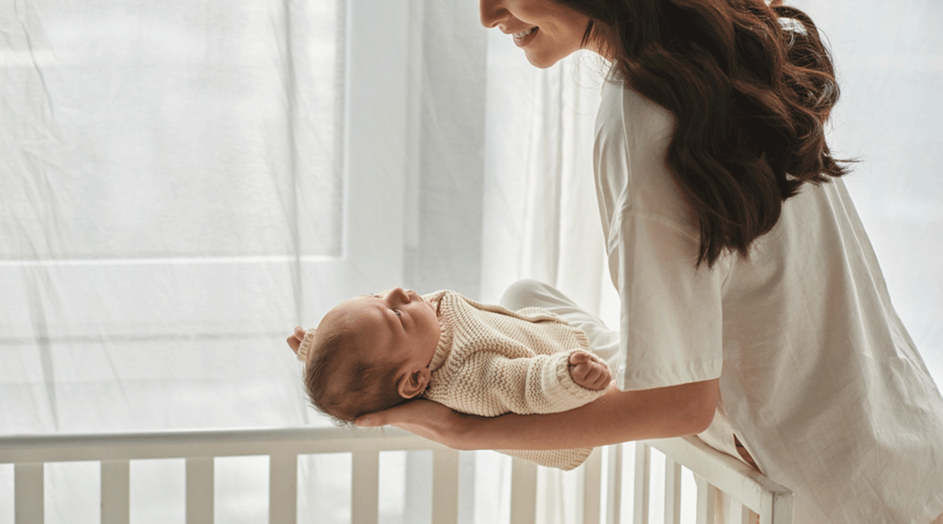 mom putting baby into crib