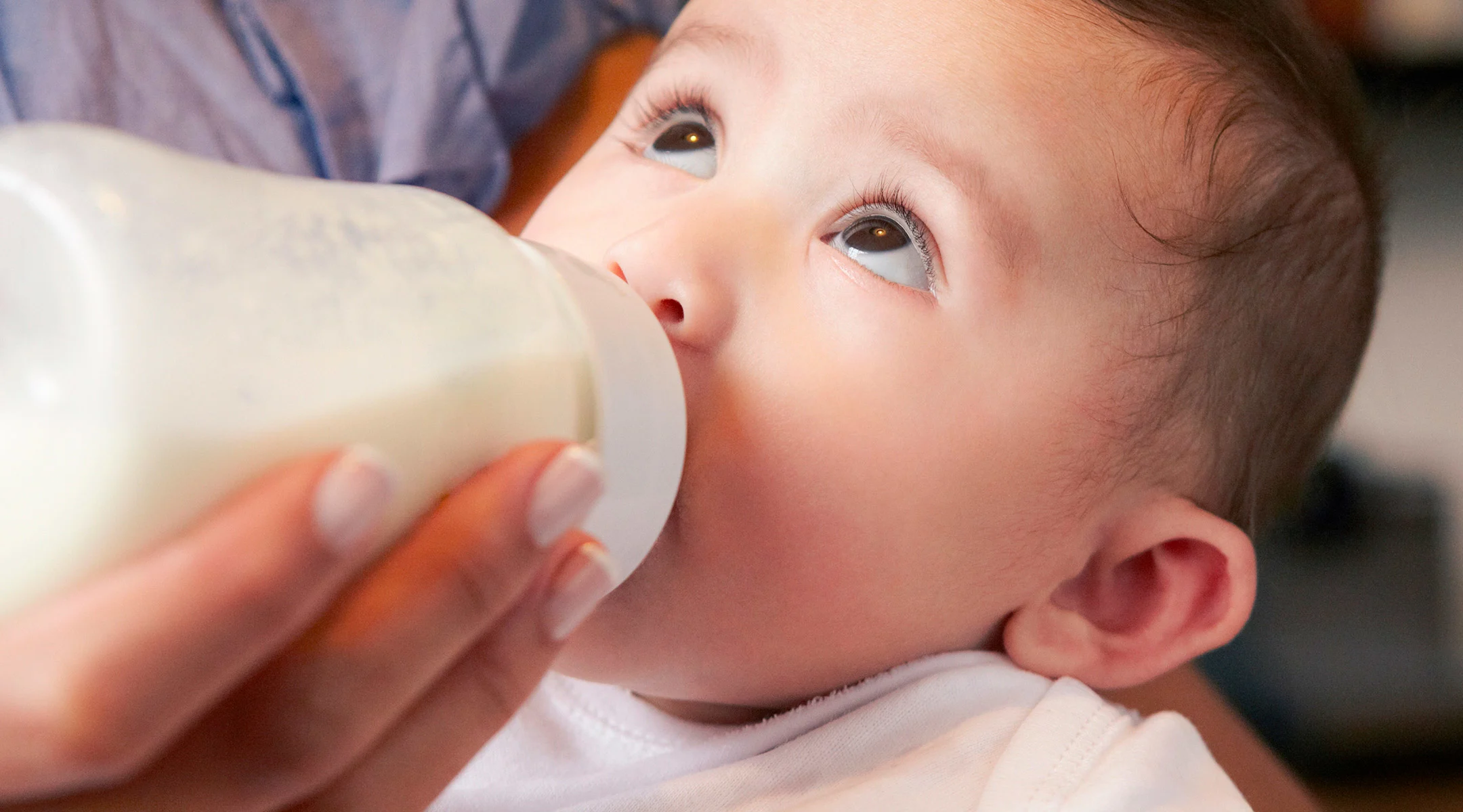 parent feeding baby from baby bottle