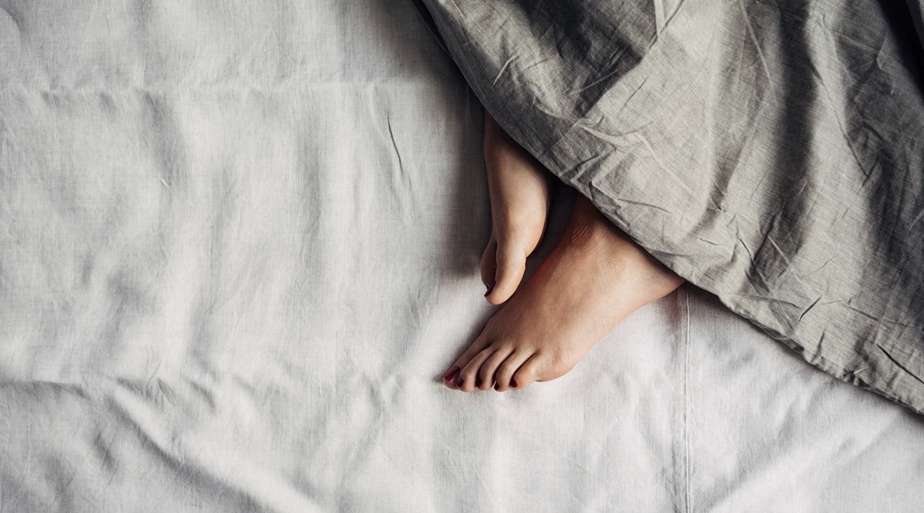 woman's feet poking out of blanket in bed