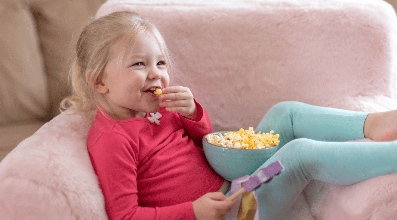 toddler girl sitting in pink lounge chair