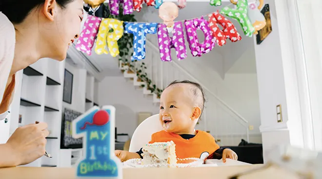 baby eating cake and smiling on first birthday