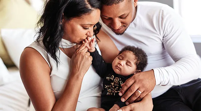 new parents kissing their newborn's hand