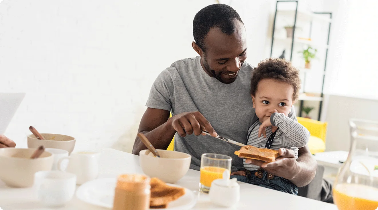 dad putting peanut butter on toast for toddler at home for breakfast