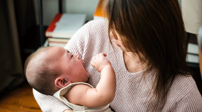 mom comforting crying baby at home