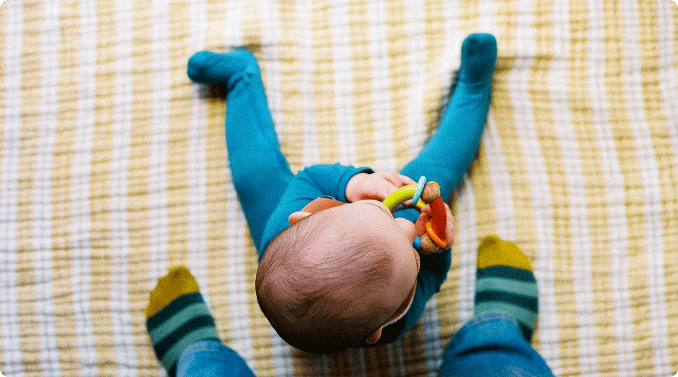 overhead view of baby sitting up at parent's feet