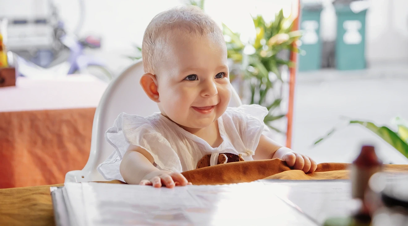 baby sitting in high chair at table outside