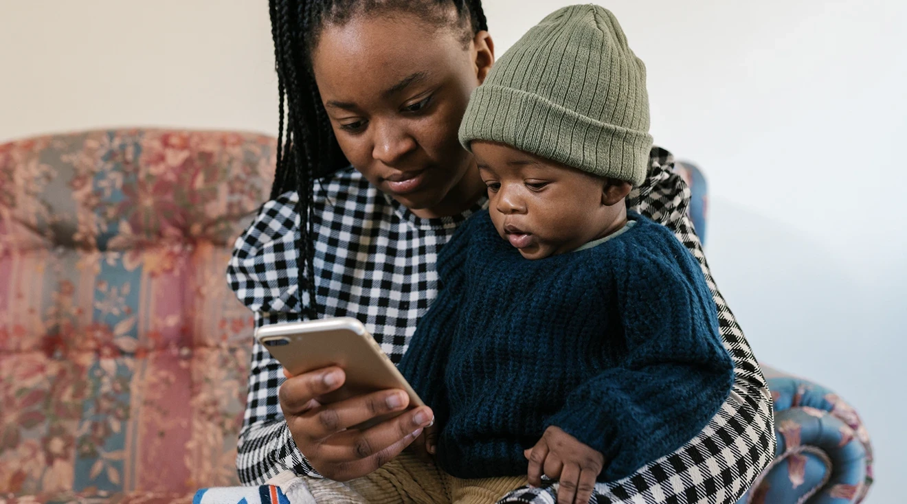 mother and baby looking at smartphone on the couch at home