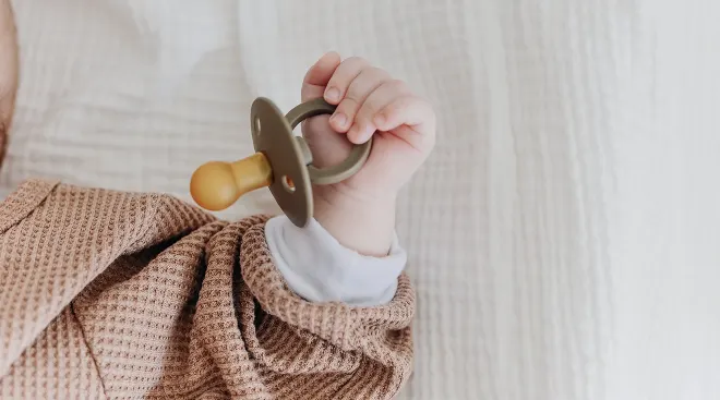 close up of baby hand holding pacifier
