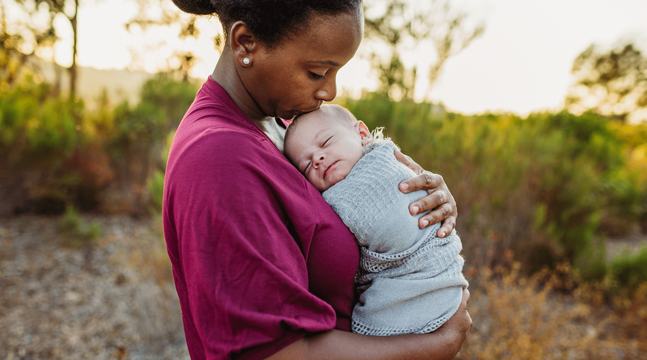 mom kissing newborn baby