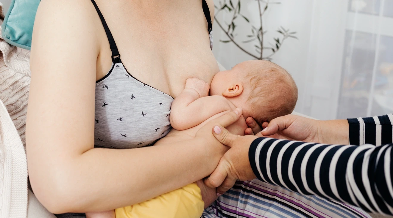 lactation consultant assisting mother with breastfeeding baby
