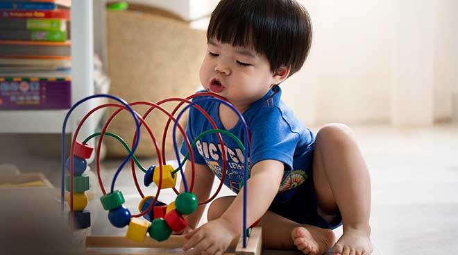 Toddler playing with wooden bead maze.