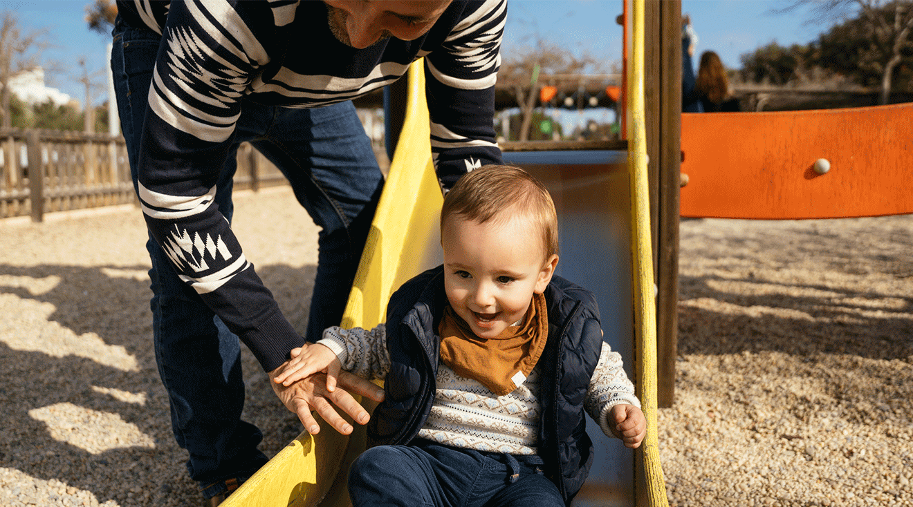 father playing with toddler at the playground