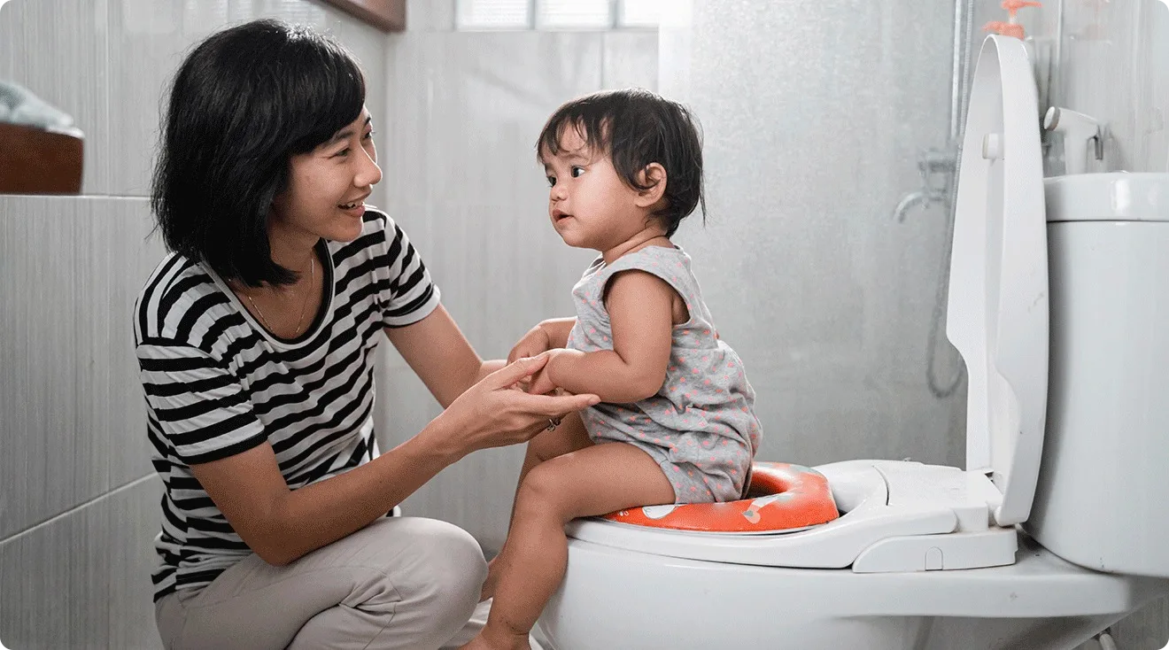 mother helping toddler use potty seat for potty training