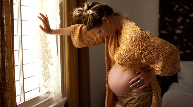 young pregnant woman experiencing labor pains while at home