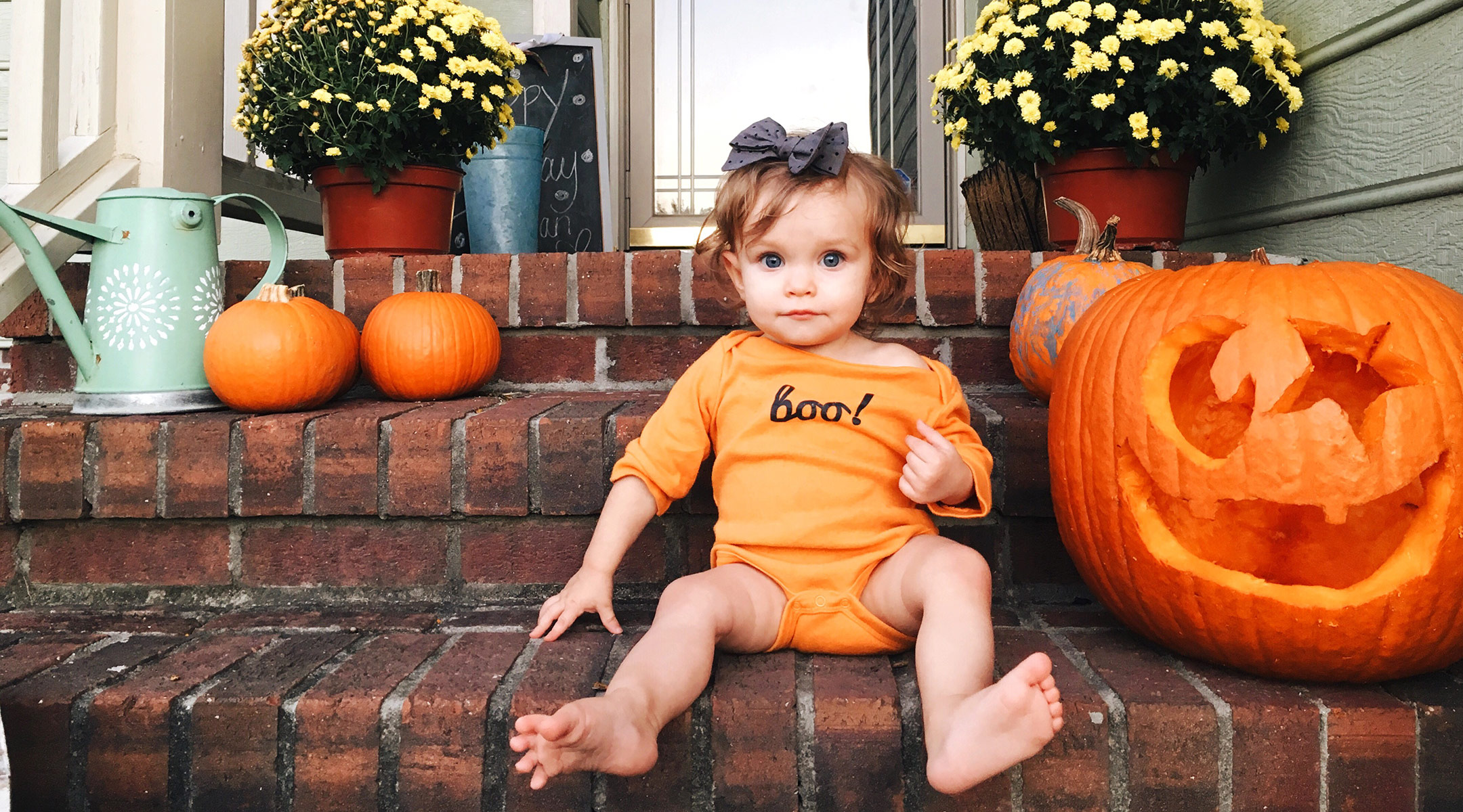 little girl sitting on steps with pumpkins